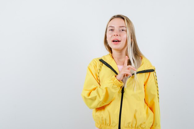 Señorita apuntando hacia arriba en camiseta, chaqueta y luciendo linda