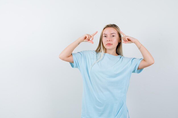 Señorita apuntando hacia arriba en camiseta y mirando confiada