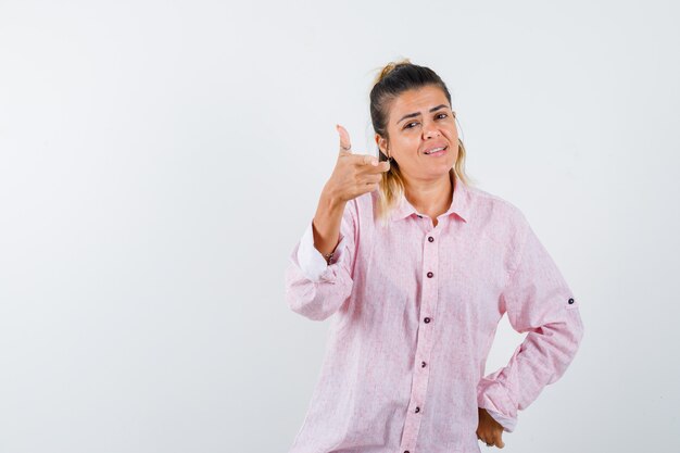 Señorita apuntando a la cámara en camisa rosa y mirando alegre