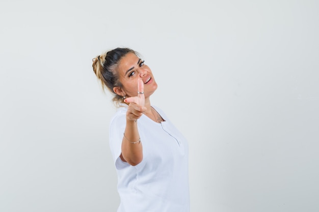 Señorita apuntando a la cámara en camiseta y mirando confiado