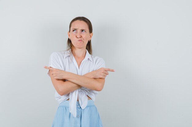 Señorita apuntando hacia fuera en blusa y falda y mirando indeciso