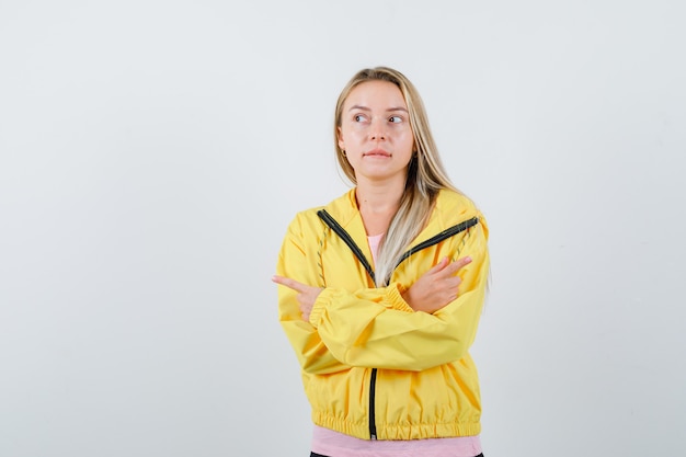 Señorita apuntando a un lado en camiseta, chaqueta y mirando pensativo