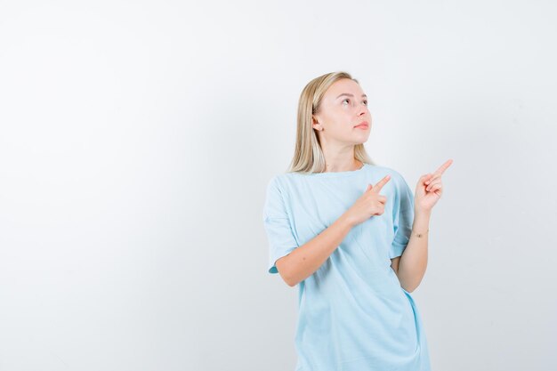 Señorita apuntando hacia el lado superior derecho en camiseta y mirando confiada