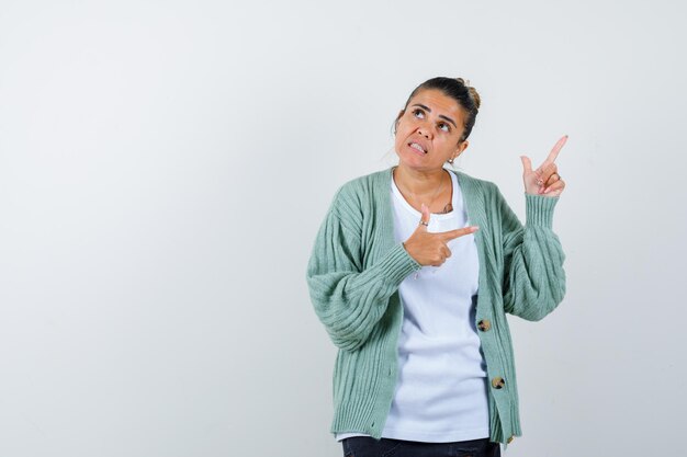 Señorita apuntando lejos en camiseta, chaqueta y mirando pensativo