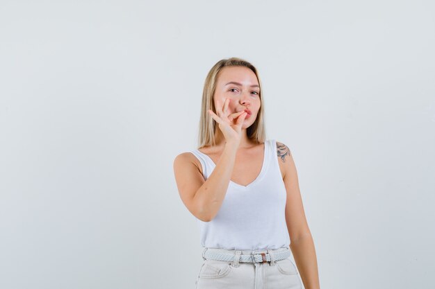 Señorita en blusa blanca que muestra un gesto delicioso y parece seguro