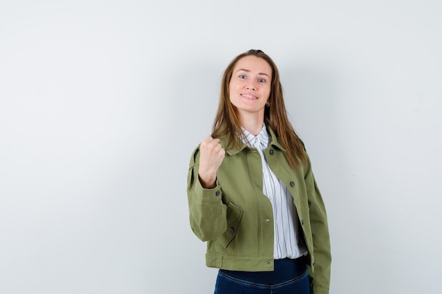 Señorita en blusa, chaqueta mostrando gesto de ganador y mirando confiado