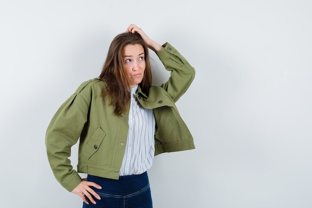 Señorita en blusa, chaqueta rascándose la cabeza y mirando vacilante