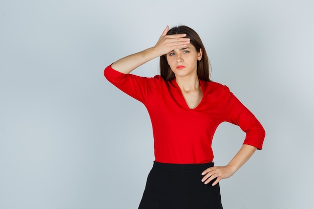 Foto gratuita señorita en blusa roja, falda con la mano en la frente