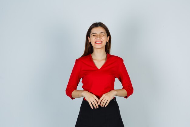 Señorita en blusa roja, falda mostrando los dientes y mirando gracioso