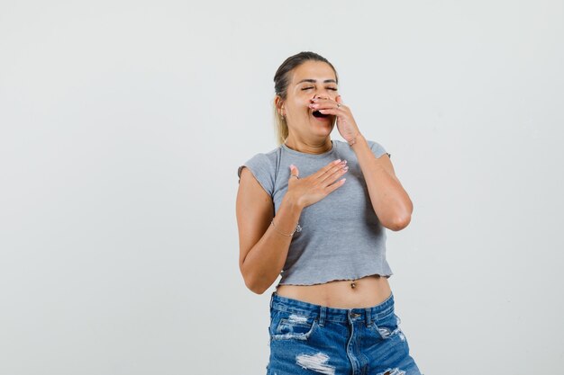 Señorita bostezando en camiseta, pantalones cortos y con sueño,