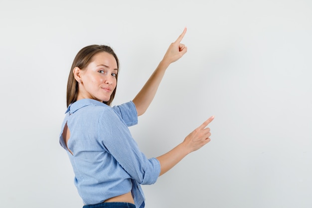 Señorita en camisa azul, pantalones apuntando hacia arriba y mirando feliz