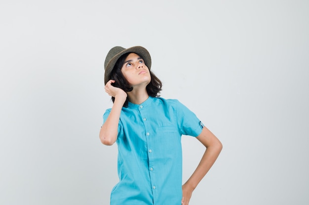 Señorita con camisa azul, sombrero mirando al cielo