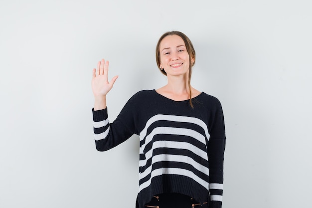 Foto gratuita señorita en camisa casual agitando la mano para saludar y mirar feliz