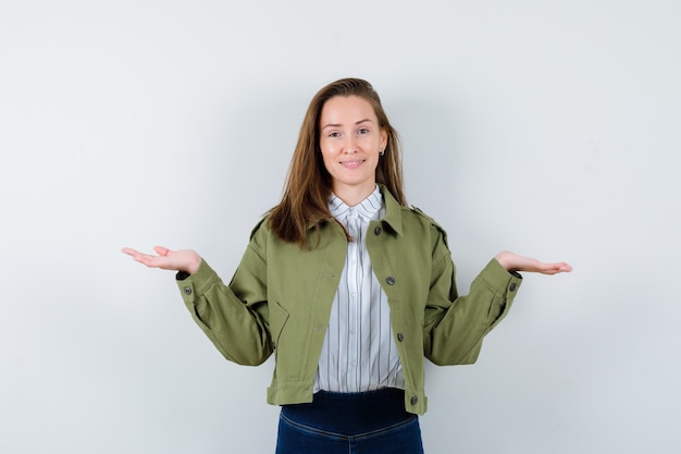 Señorita en camisa, chaqueta haciendo gesto de escamas y mirando alegre, vista frontal.