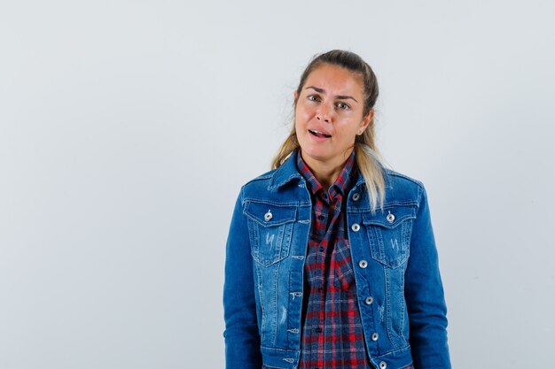 Señorita en camisa, chaqueta mirando a la cámara y mirando perplejo, vista frontal.