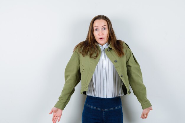 Señorita en camisa, chaqueta mostrando gesto de impotencia encogiéndose de hombros y mirando confundido, vista frontal.