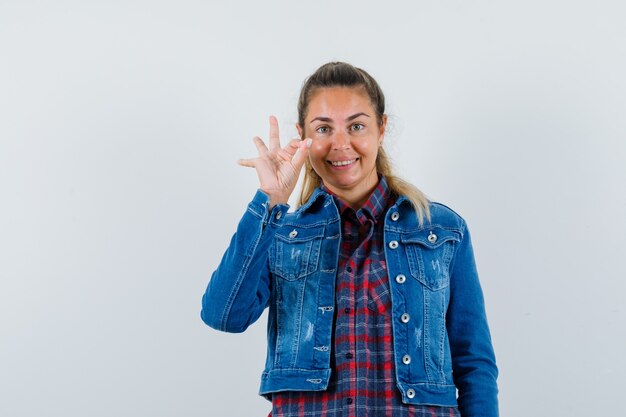 Señorita en camisa, chaqueta mostrando gesto ok y mirando alegre, vista frontal.