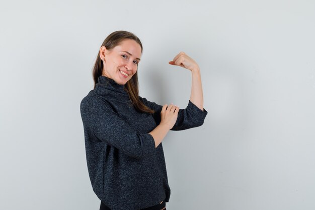 Señorita en camisa mostrando los músculos del brazo y luciendo orgullosa