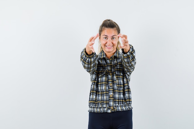 Señorita en camisa, pantalones cortos abriendo los brazos para abrazar y luciendo feliz, vista frontal.