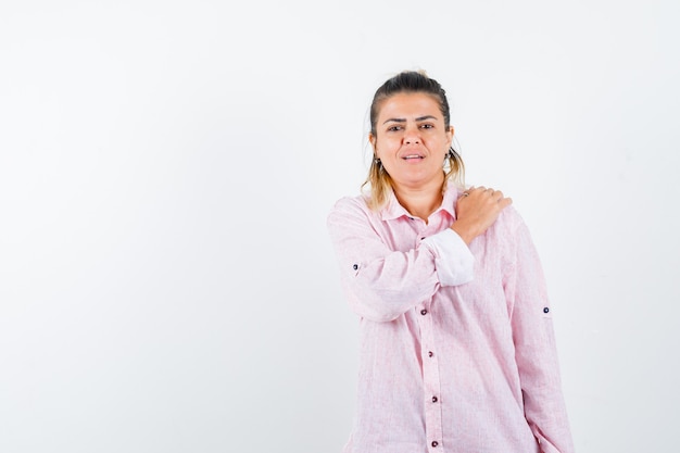 Señorita en camisa rosa manteniendo la mano en el hombro y mirando pensativo