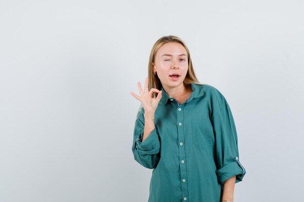 Señorita en camisa verde mostrando gesto ok y mirando confiado