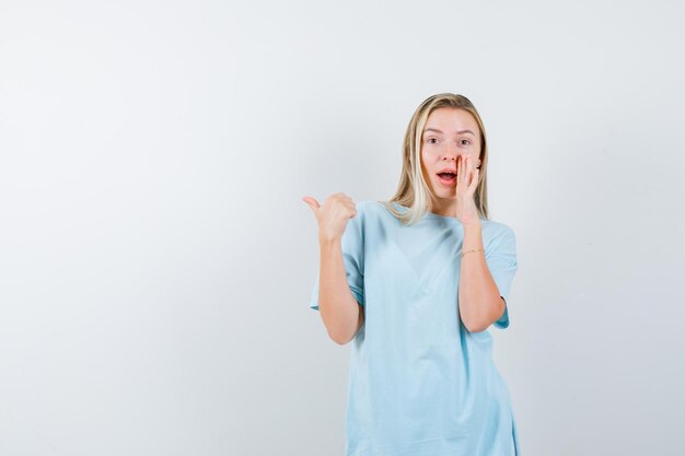 Señorita en camiseta apuntando hacia el lado izquierdo con el pulgar aislado