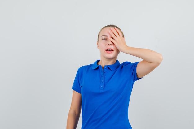 Señorita en camiseta azul con la mano en el ojo