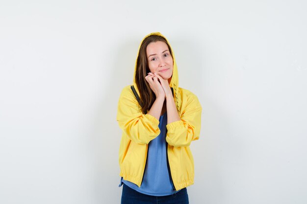 Señorita en camiseta, chaqueta apoyando la barbilla en las manos juntas y luciendo bonita