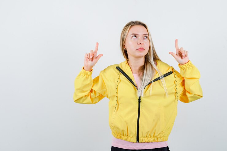 Foto gratuito señorita en camiseta, chaqueta apuntando hacia arriba y mirando enfocado