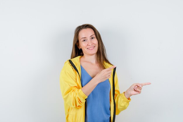 Señorita en camiseta, chaqueta apuntando hacia el lado derecho y mirando confiada, vista frontal.