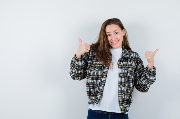 Foto gratuita señorita en camiseta, chaqueta mostrando doble pulgar hacia arriba y mirando feliz, vista frontal.