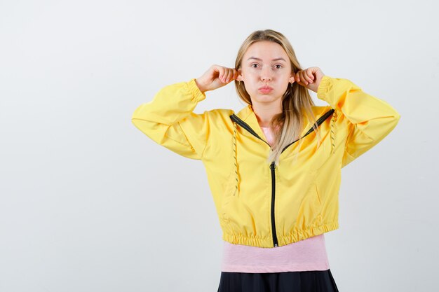 Señorita en camiseta, chaqueta mostrando gesto gracioso mientras sopla las mejillas y se ve gracioso