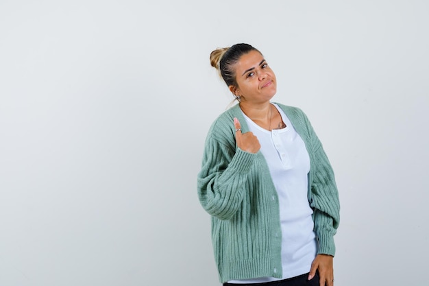 Señorita en camiseta, chaqueta mostrando el pulgar hacia arriba y mirando confiado