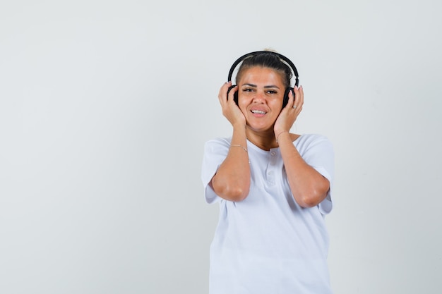 Señorita en camiseta escuchando música con auriculares