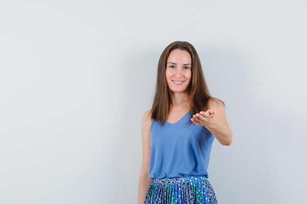 Señorita en camiseta, falda estirando la mano y mirando alegre