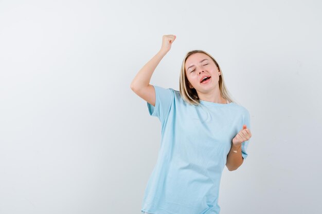 Señorita en camiseta mostrando gesto ganador y mirando dichoso aislado