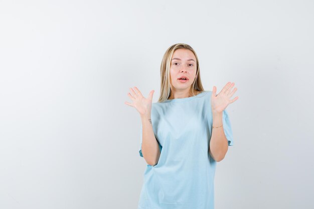 Señorita en camiseta mostrando palmas en gesto de rendición y mirando desconcertado aislado