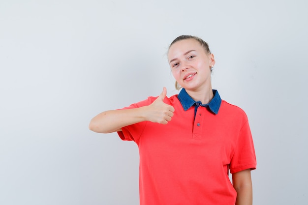 Señorita en camiseta mostrando el pulgar hacia arriba y mirando feliz