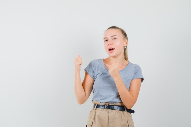 Señorita en camiseta y pantalón mostrando gesto de ganador y con suerte