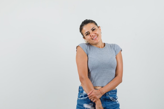 Señorita en camiseta, pantalones cortos posando mientras está de pie y se ve linda