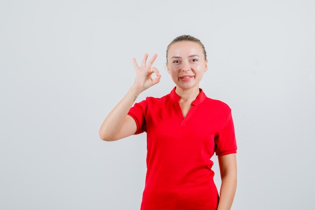 Señorita en camiseta roja mostrando gesto ok y mirando complacido