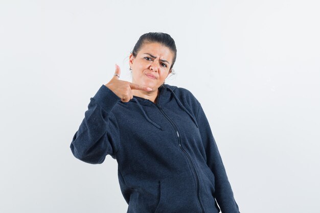 Señorita en chaqueta apuntando a un lado y mirando disgustado