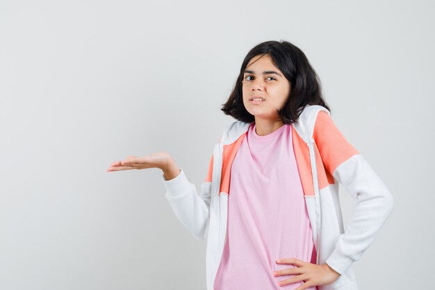 Señorita en chaqueta, camisa rosa extendiendo su palma a un lado, mostrando algo y mirando insatisfecho