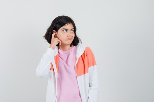 Señorita en chaqueta, camisa rosa mirando a un lado mientras piensa y parece sin sentido