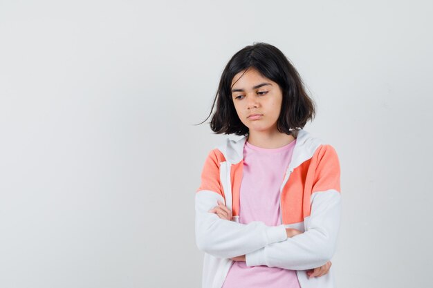 Señorita en chaqueta, camisa rosa de pie con los brazos cruzados y mirando ofendido