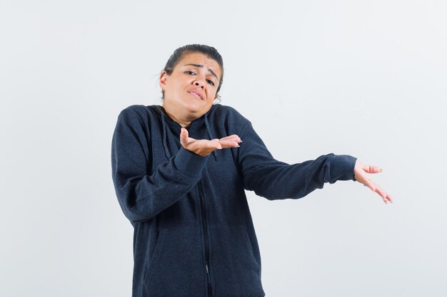 Señorita en chaqueta mostrando gesto de impotencia y mirando insatisfecho