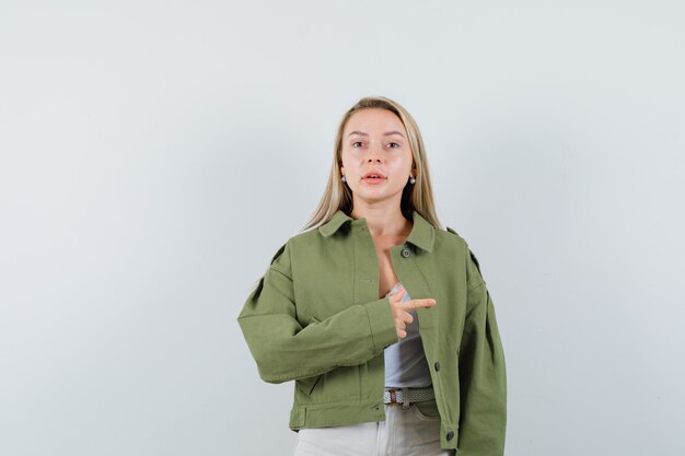 Señorita en chaqueta, pantalones apuntando hacia el lado derecho y mirando confiada, vista frontal.