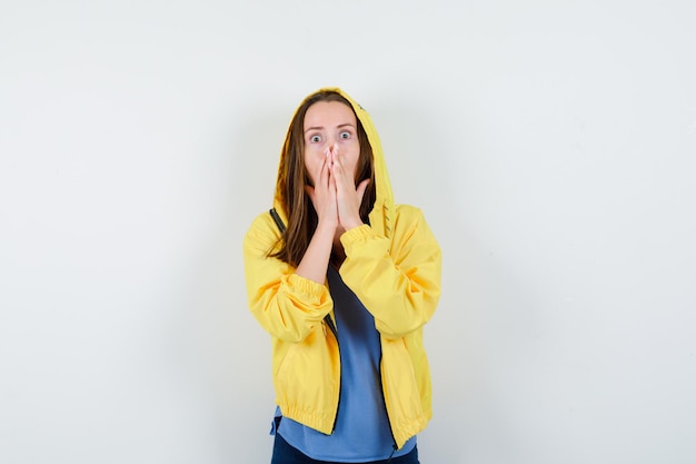 Señorita cogidos de la mano en la boca en camiseta, chaqueta y mirando asustado