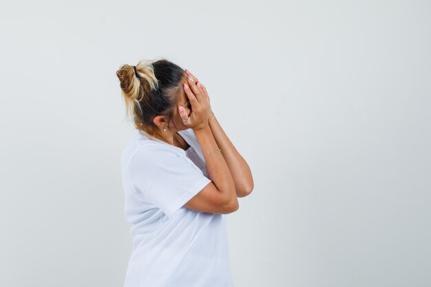 Foto gratuita señorita cogidos de la mano en la cara en camiseta y mirando avergonzado