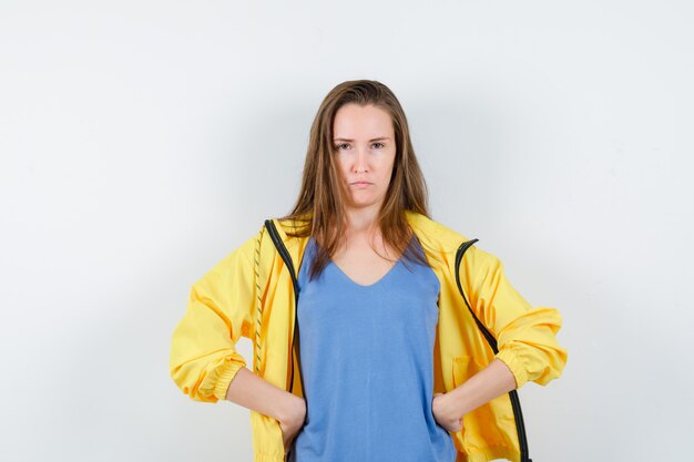 Señorita cogidos de la mano en la cintura en camiseta, chaqueta y mirando rencoroso